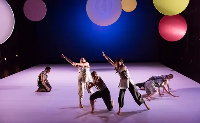 Four dances onstage with a backdrop of colored circles